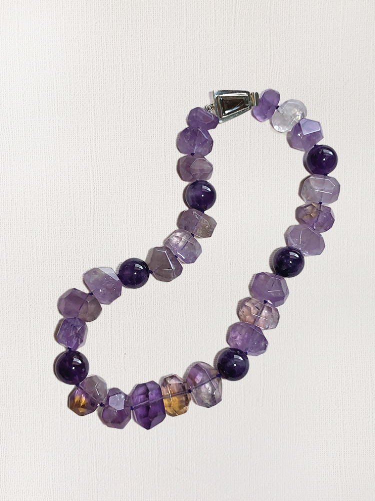 A women's beaded necklace made with amethyst and citrine nuggets, along with round amethyst beads.