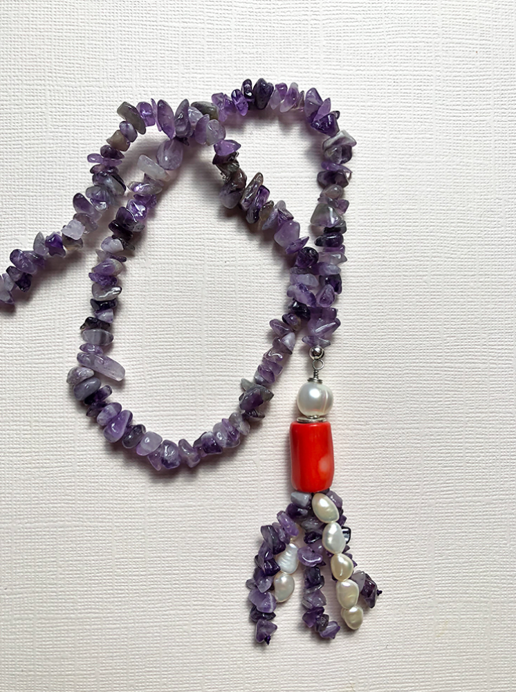 A women's lariat necklace featuring amethyst and tassel made of orange sea bamboo coral and cultured pearls.