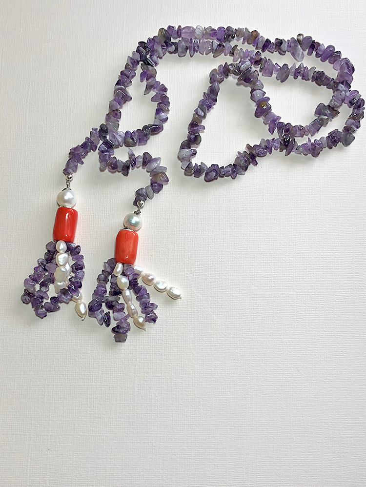 A women's lariat necklace featuring amethyst and tassel made of orange sea bamboo coral and cultured pearls.